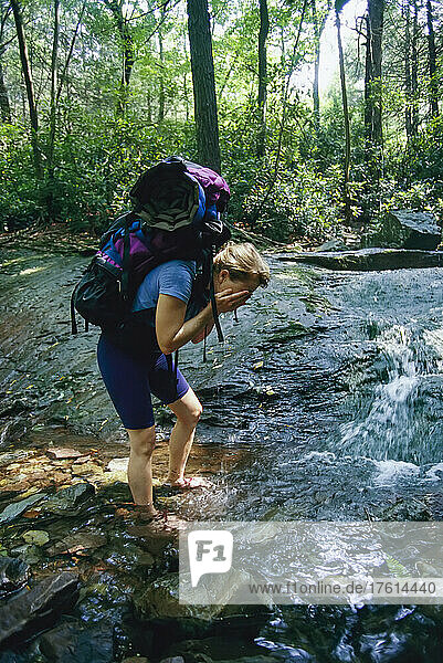 Frau hält während einer Wanderung auf dem Appalachian Trail am Bach an  um sich das Gesicht zu waschen; Gap  Pennsylvania.
