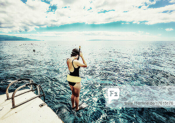 Frau  die von einem Boot mit Schnorchelausrüstung ins Wasser springt  um sich anderen Schnorchlern an der Küste von Maui anzuschließen; Maui  Hawaii  Vereinigte Staaten von Amerika