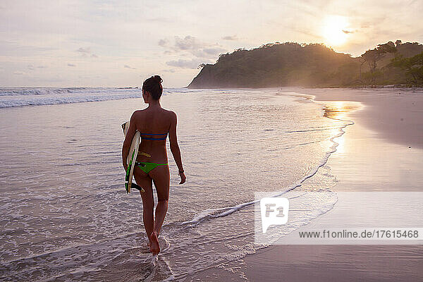 Eine junge Frau bereitet sich an einem Strand in Costa Rica auf das Surfen vor.