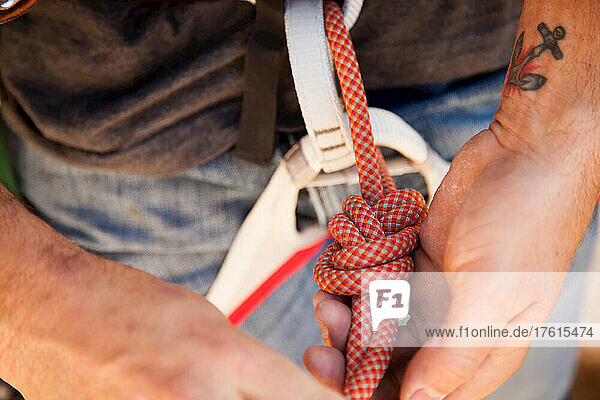Ein Kletterer bindet ein Seil mit einem Achterknoten.
