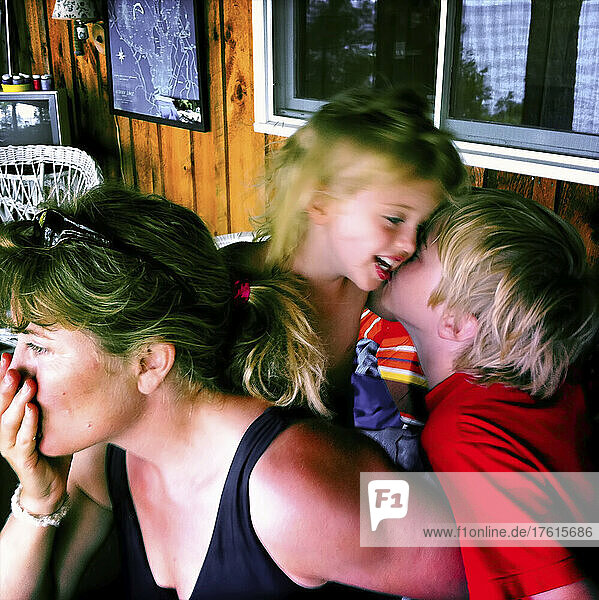 Mutter hält inne  während ihr achtjähriger Sohn seine zweijährige Schwester am Sebago Lake  Maine  küsst; Sebago Lake  Maine  Vereinigte Staaten.