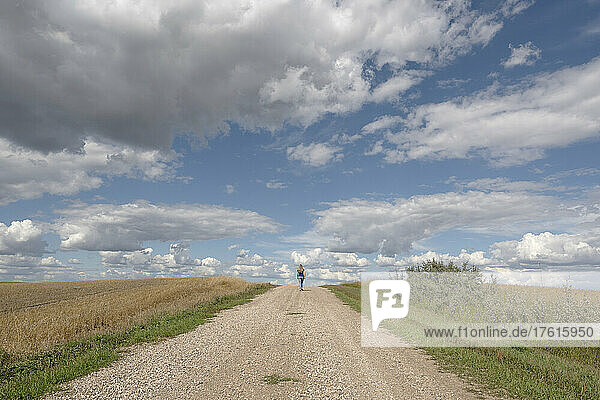 Woman walking on a gravel road in rural Saskatchewan; Saskatchewan  Canada