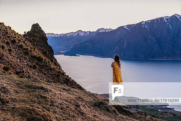 Ein Wanderer beobachtet den Sonnenaufgang über einem Alpensee.