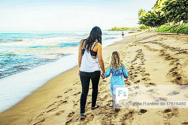 Blick von hinten auf eine Mutter und ihre Tochter  die händchenhaltend am Ka'anapali Beach spazieren gehen; Ka'anapali  Maui  Hawaii  Vereinigte Staaten von Amerika
