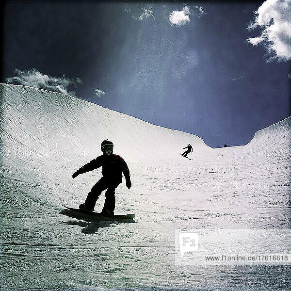 An eleven year old boy and his Mom snowboarding in a large half-pipe.; Winter Park  Colorado.