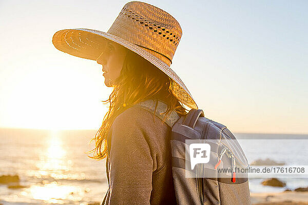 Eine Frau mit einem Strohhut bei Sonnenuntergang.