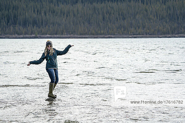Frau balanciert spielerisch auf einem Felsen in Bennett Lake; Carcross  Yukon  Kanada