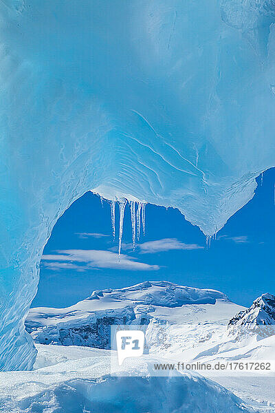 Blick unter einem blauen Eisbogen auf einen Eisberg.