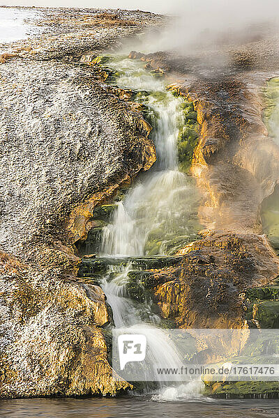 Dramatischer Blick auf aufsteigenden Dampf und Wasser  das durch den thermischen Abflusskanal in den Firehole River am Excelsior Geysir im Midway Geysir Basin fließt; Yellowstone National Park  Wyoming  Vereinigte Staaten von Amerika
