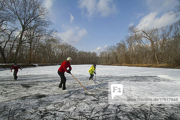 Eine Mutter und ihre beiden Kinder spielen Teichhockey auf dem zugefrorenen C&O-Kanal; Chesapeake and Ohio Canal. Potomac  Maryland.