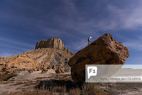 Ein Mann auf einem Felsen unter dem Nachthimmel in der Wüste.