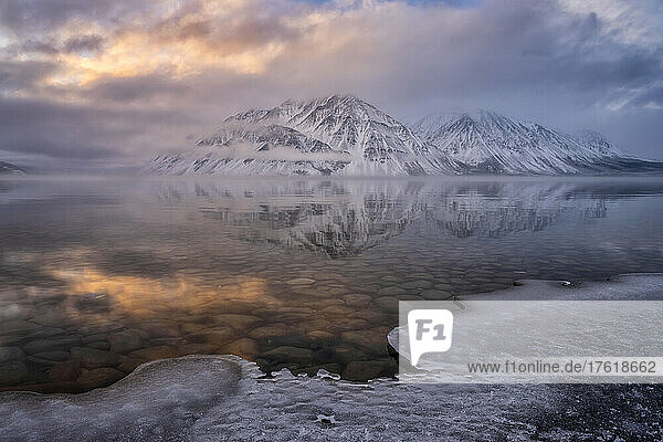 Der schneebedeckte Mount Worthington spiegelt sich in den stillen Wassern des Kathleen Lake mit nebligen  tief hängenden Wolken und Farben  die eine stimmungsvolle Atmosphäre schaffen; Haines Junction  Yukon  Kanada