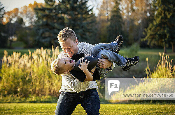 Father playing with his young son in a park in autumn; St. Albert  Alberta  Canada