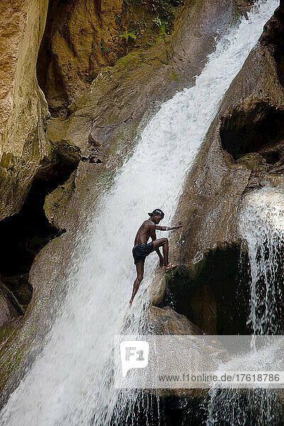 Ein Mann erklimmt den Wasserfall im Basin Bleu.