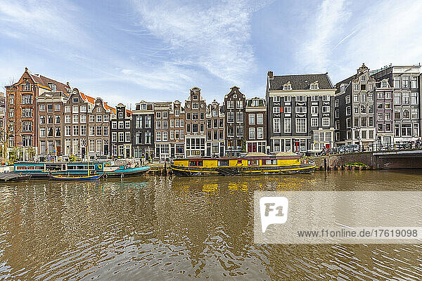 Auf dem Singelkanal vor traditionellen Häusern in Amsterdam vertäute Lastkähne; Amsterdam  Nordholland  Niederlande