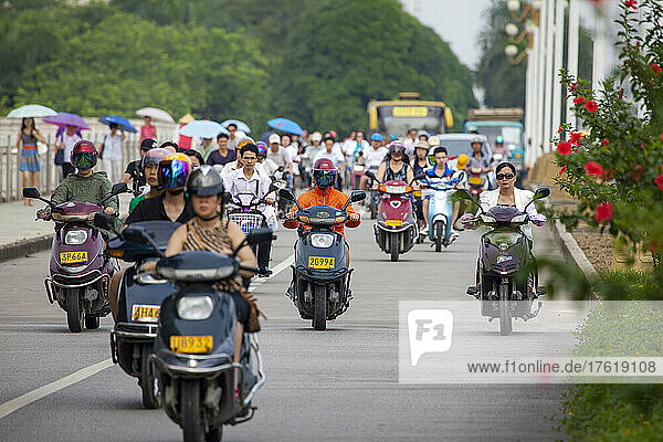 Menschen  die frühmorgens auf Fahrrädern und Motorrollern auf einer separaten Spur in der Stadt Nanning  Guangxi  Südwestchina  pendeln; Nanning  Guangxi  China