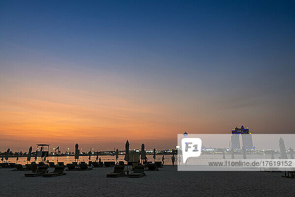A beach club beneath the setting sun in the Persian Gulf with a view of Marina Island; Abu Dhabi  United Arab Emitarites