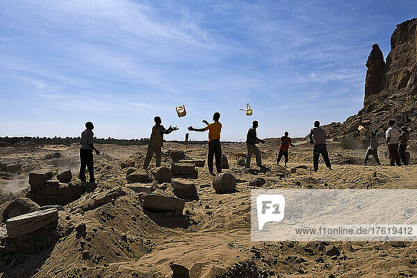 Sudanesische Arbeiter werfen sich gegenseitig Eimer zu  um den Sand effizient zu transportieren und archäologische Überreste zu erhalten; Meroe  Sudan  Afrika.