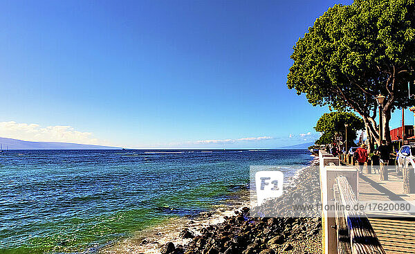 Pedestrians walk on the wooden boardwalk along the water's edge in Lahaina with a view of Island of Lanai in the background; Lahaina  Maui  Hawaii  United States of America