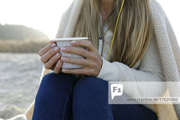 Blond woman in warm clothing holding tea cup