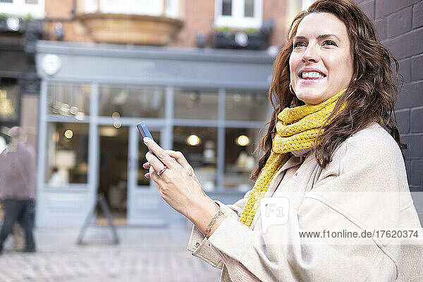 Happy young woman holding mobile phone