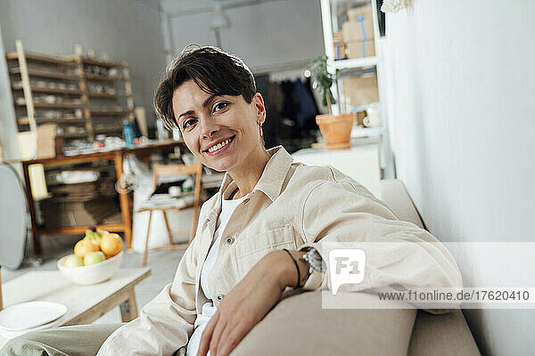 Smiling entrepreneur sitting in ceramics store