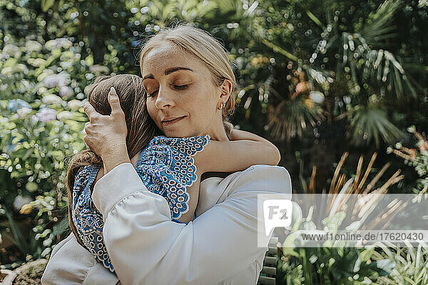 Mother embracing daughter in back yard
