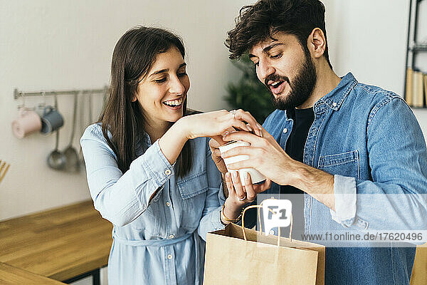 Smiling woman and man holding box standing in kitchen at home
