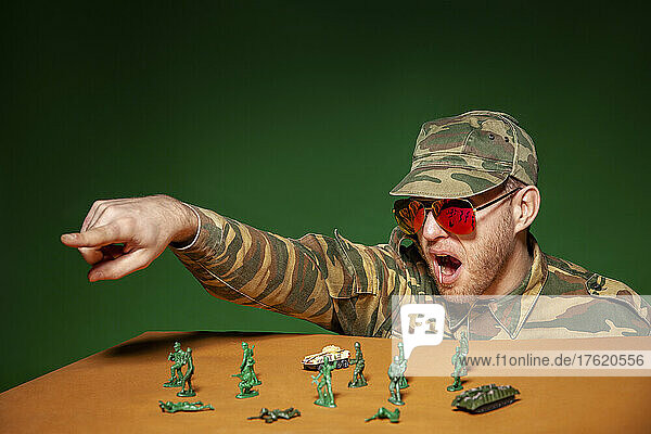 Army soldier playing with figurine toys against green background