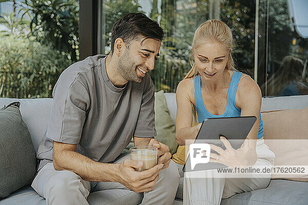 Woman sharing smart phone with man holding coffee cup at lounge