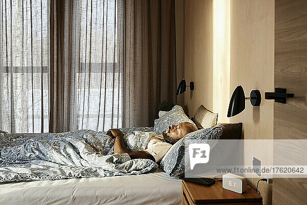 Man sleeping on cozy bed in morning at home