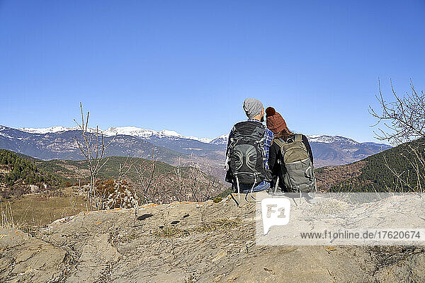 Paar sitzt zusammen auf einem Felsen und genießt die Aussicht