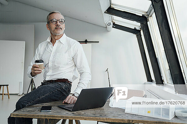 Contemplative architect with disposable cup in office