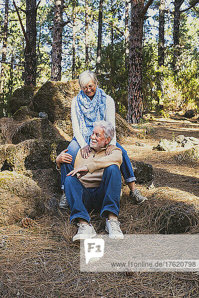 Happy senior couple sitting on rocks in forest