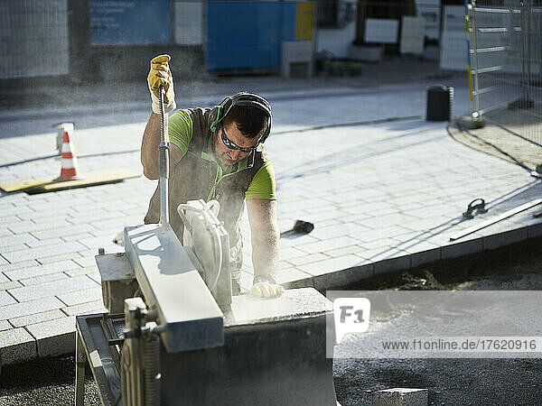 Craftsperson cutting paving stone on industrial equipment