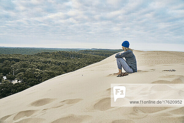 Woman sitting on sand dune at vacation