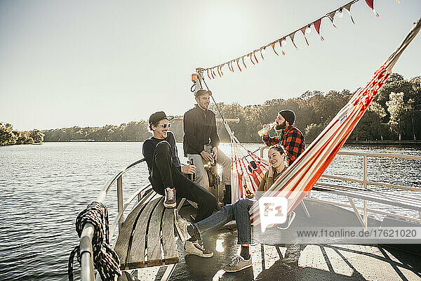 Happy friends talking with each other sitting on boat bow