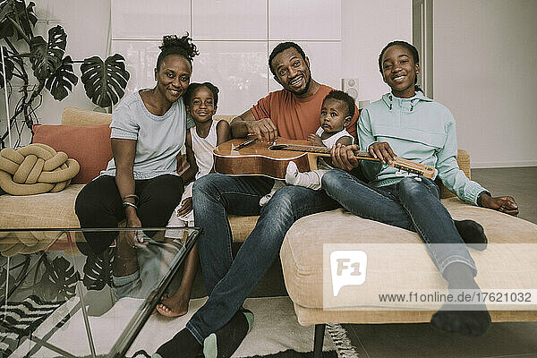 Smiling family with guitar sitting on couch