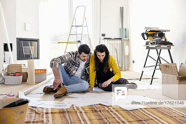 Young couple examining floor plans at new home