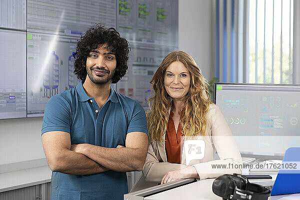 Lächelnde Geschäftsfrau mit Techniker am Schreibtisch im Kontrollraum