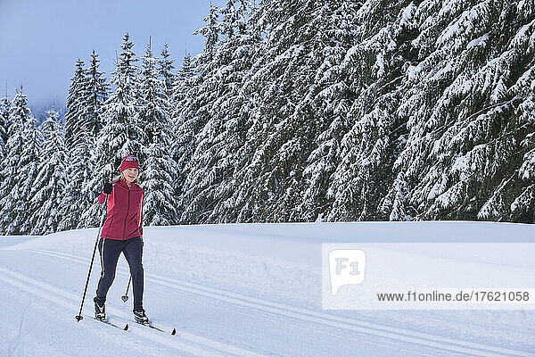 Senior woman skiing in winter forest