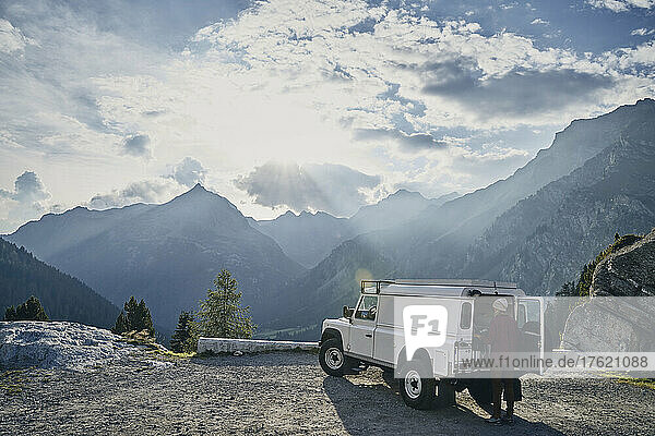 Tourist steht an einem sonnigen Tag neben einem Geländewagen  Kanton Graubünden  Malojapass  Schweiz