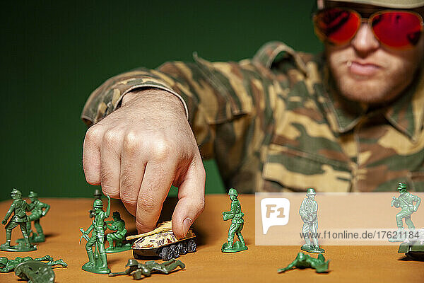 Military soldier arranging armored tank on table