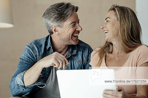 Cheerful woman and man sitting with laptop at home