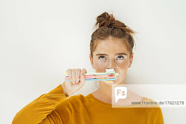 Woman holding toothbrushes against white background