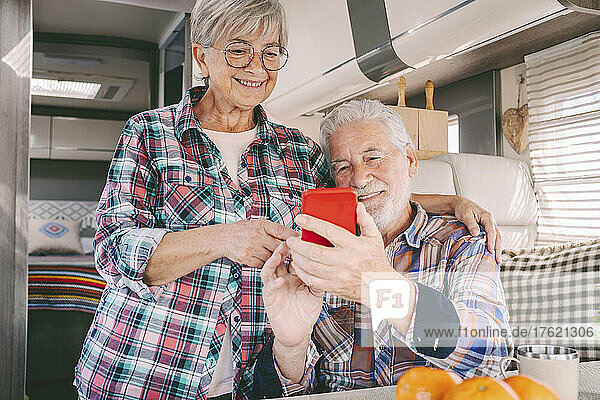 Smiling senior couple using smart phone at motor home