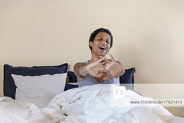 Woman yawning and stretching on bed in bedroom