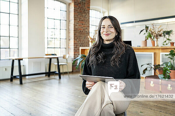 Happy businesswoman with tablet PC at home office
