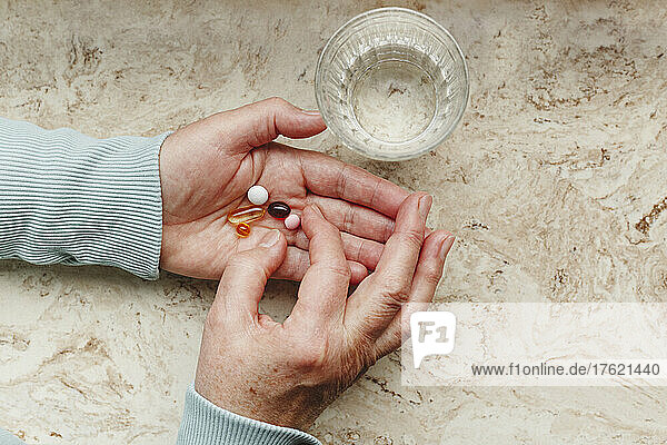 Senior woman taking medicinal pills with glass of water