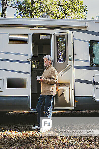 Älterer Mann mit Kaffeetasse steht an der Tür des Wohnmobils